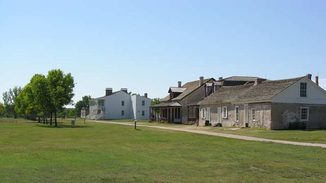 Historic wooden fort set in a grassy field.
