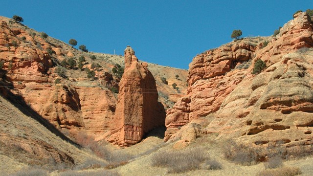 Red, sandstone cliffs, highly-eroded, with an eroded ravine.