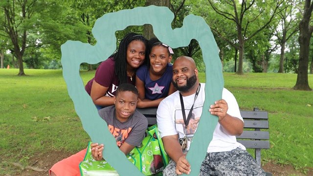 Family holding a cutout of the NPS arrowhead