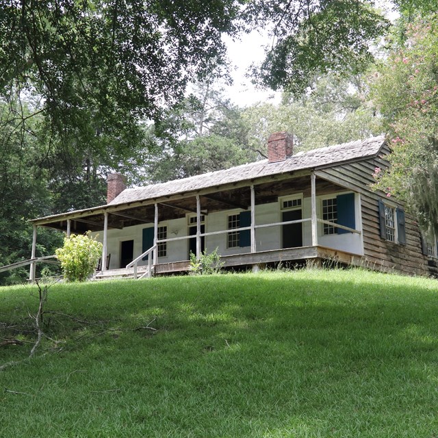 A cabin on a hill with trees all around.