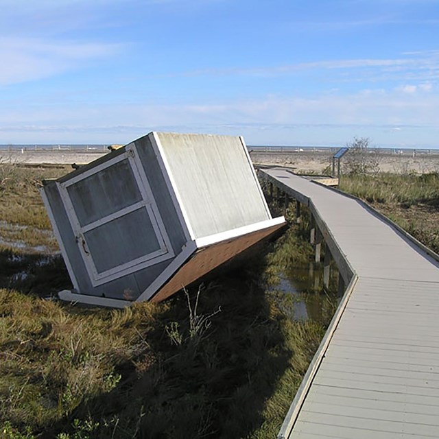 a bike shed is upside down next to a boardwalk