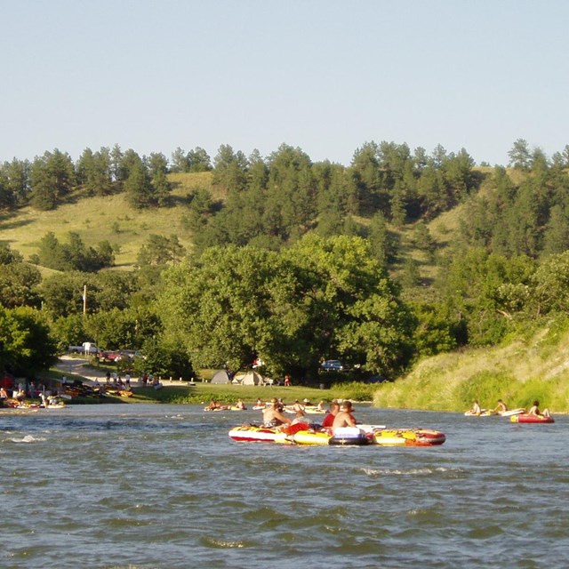 A group of tubes float on the river as the sun begins to set.