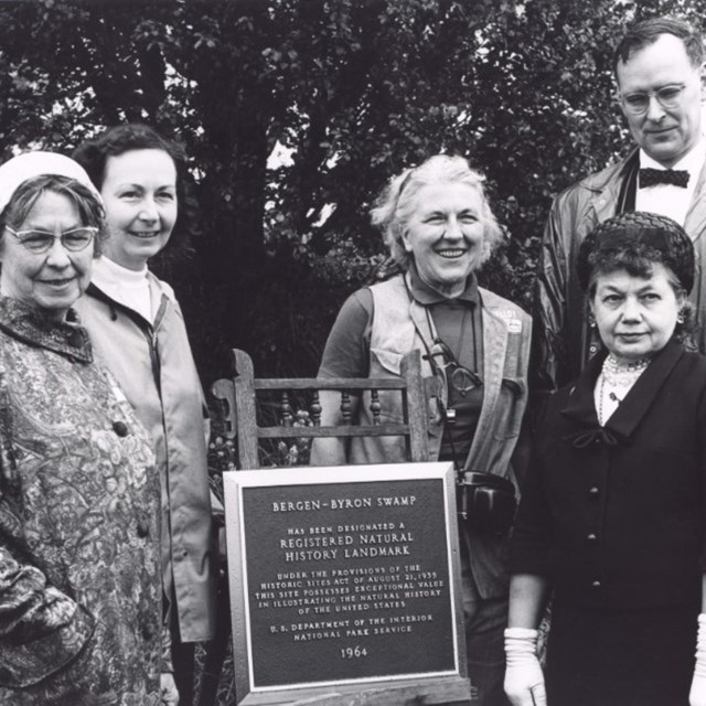 historic photo of people next to plaque