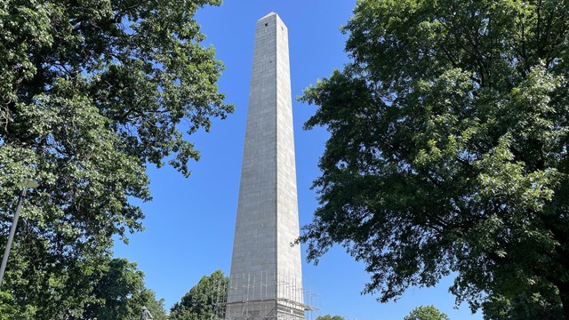 A tall, stone monument with scaffolding at its base.