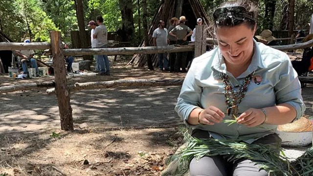 Ranger Emily sitting and weaving a basket