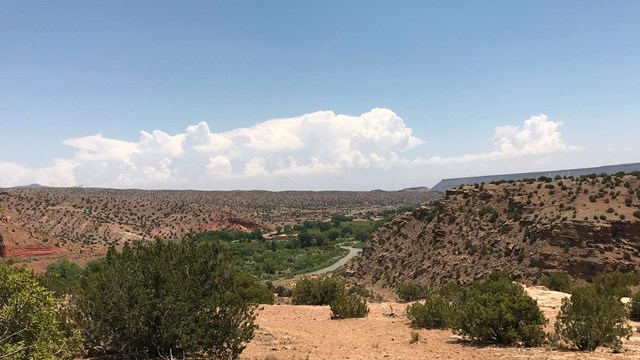 Looking out onto a distant river, flowing through a desert, red rock canyon.