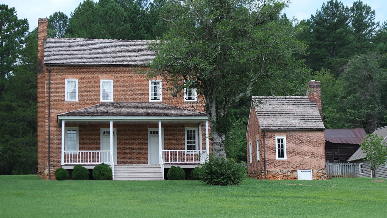 A brick two story house with small brick building beside it