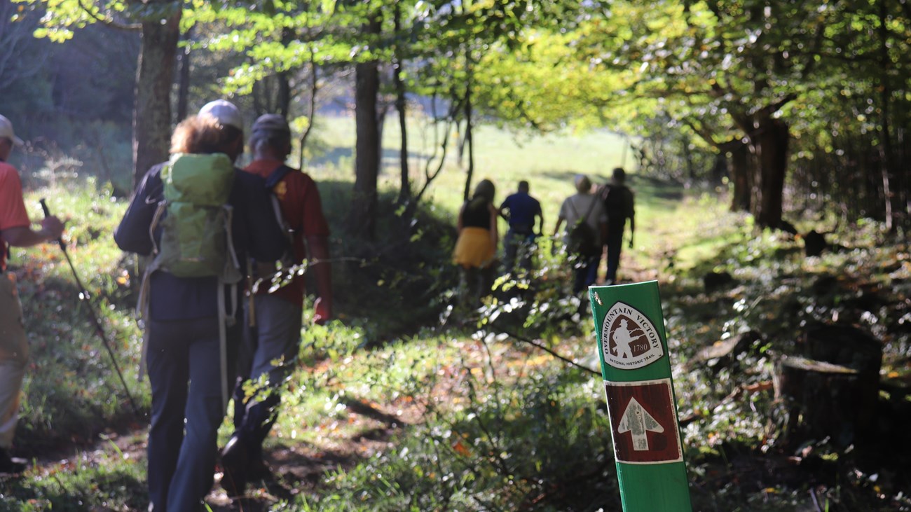 A group of hikers passing a trail marker