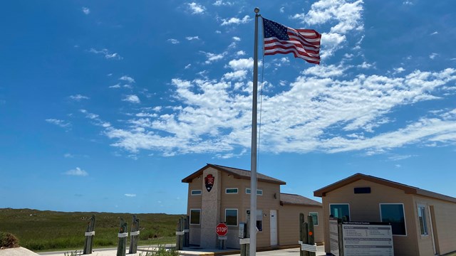 A small fee booth with a US flag flying overhead. 