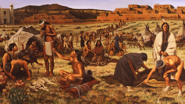 Many ancestral pueblo people trading with nomadic peoples, two four-story pueblo buildings beyond.