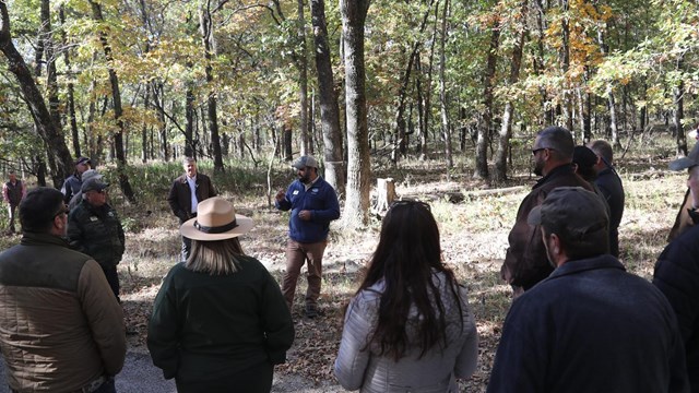 Photo of a speaker talking to visitors at trail head.