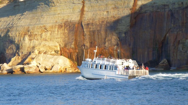 A white boat cuts through a calm Lake Superior