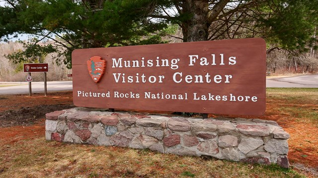 A brown sign reading "Munising Falls Visitor Center".