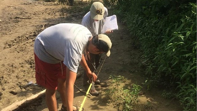 Two volunteers work on the shores of the Potomac River.