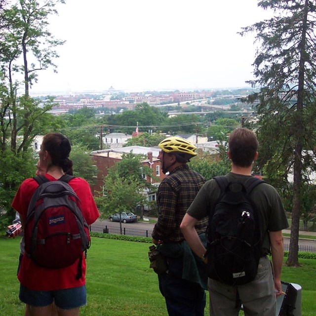 Four people standing on a hill overlooking a city.