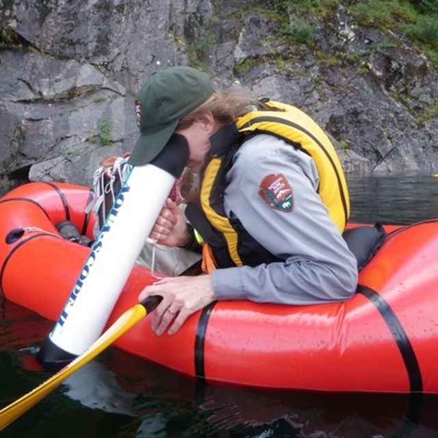 Ranger looks through scope into water. 