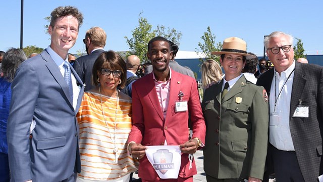 Several people stand together smiling on the Pullman State Historic Site grounds.