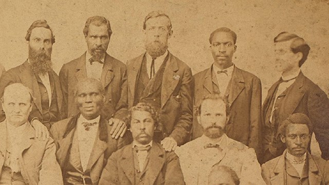 A black and white photograph of eleven men wearing suits.