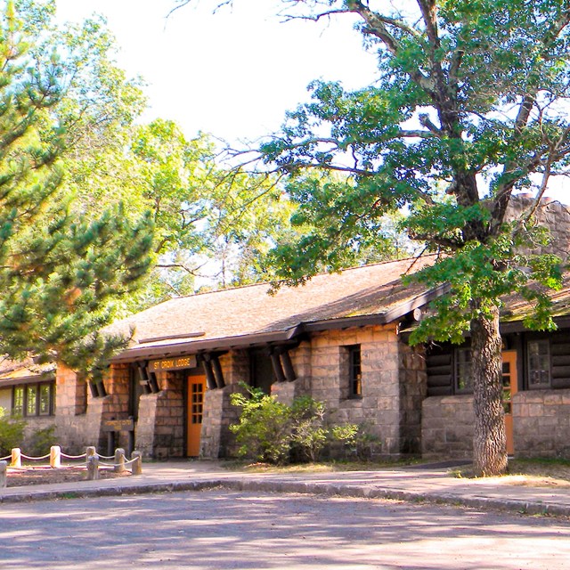 A stone and timber building sits under trees.