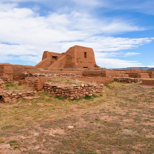 Adobe ruins, weathered and partial, in a desert setting with light scrub.