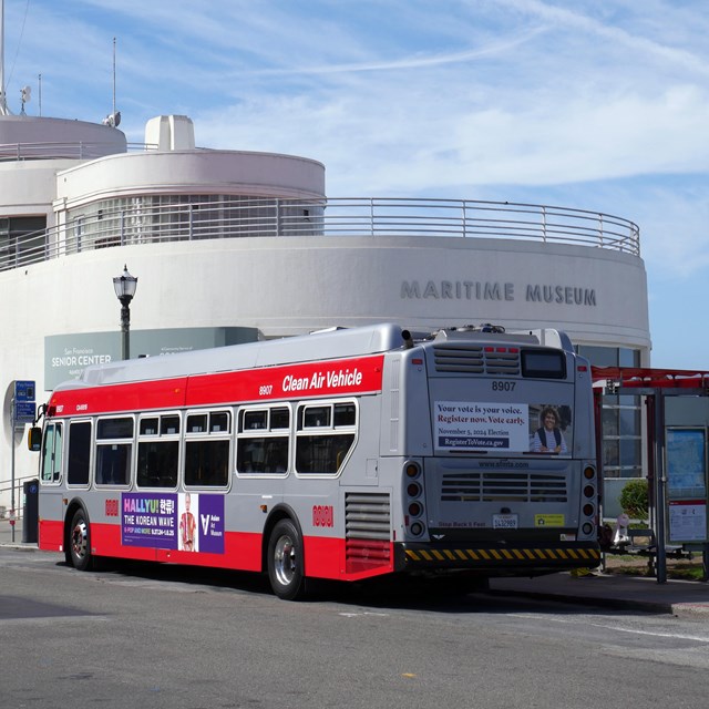 A SF city bus stops in front of the Maritime Museum