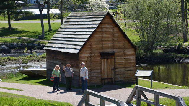 People stand next to a wooden structure.