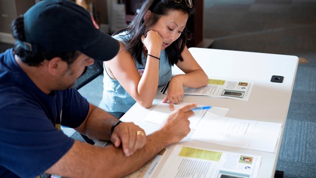 Two people sit at a desk reviewing primary source documents.