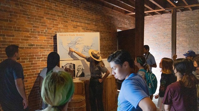 Park ranger points to a map, standing with a group of students. 