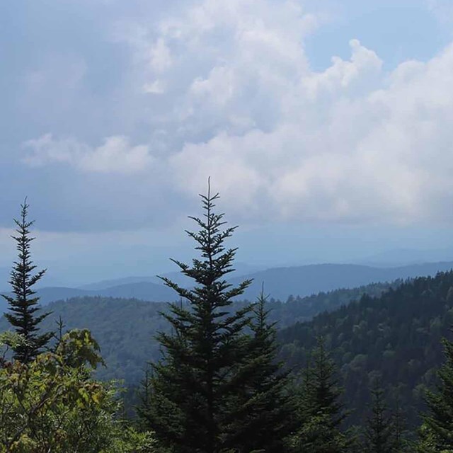 A mountain range with clouds and somewhat hazy sky.