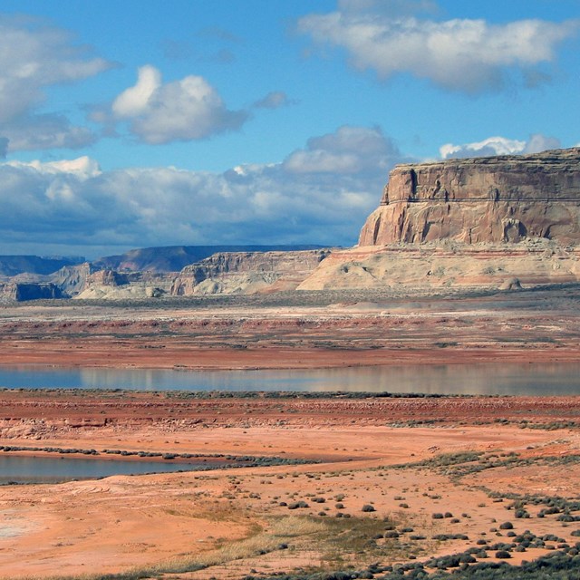 Lake reflecting clouds in the sky with canyon buttes in the distance.