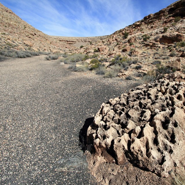 Flat, sandy area surrounded by hills dotted with shrubs