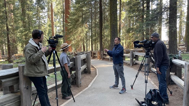 People with video camera film a National Park Service ranger being interviewed.