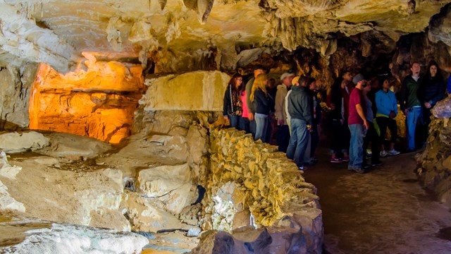 A group of people in a cave room near a stream. Photo by Alison Taggart-Barone.