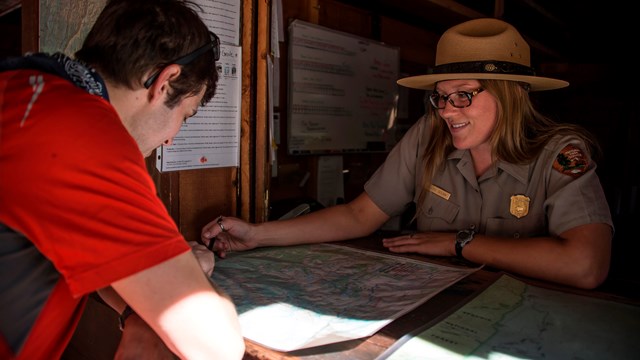 A ranger at a desk talks with a person. Photo by Alison Taggart-Barone.