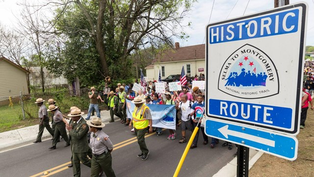 A large group of marchers walking with SEMO NHT banner to commemorate the anniversary of the march