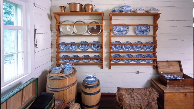 Historic china on a table with a ranger and tour group in the background