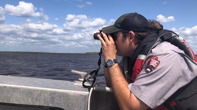 ranger looking through binoculars on water 