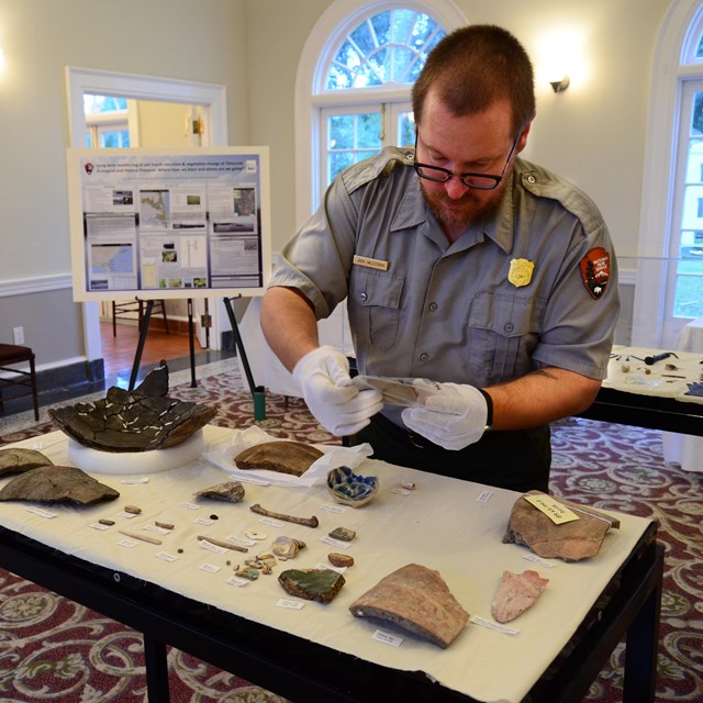 white gloved museum tech handles pot pieces