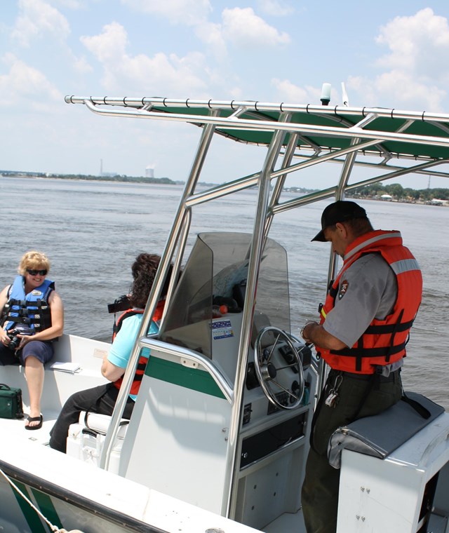 ranger in life vest at helm of boat