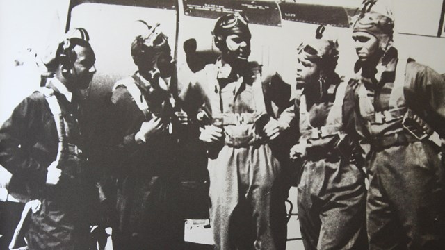 Five men standing in front of an airplane