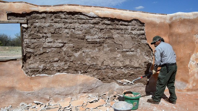 park ranger doing maintenance on exposed adobe wall