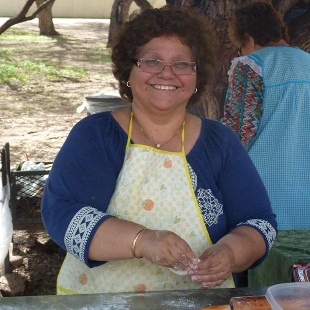 woman smiling standing behind steel table