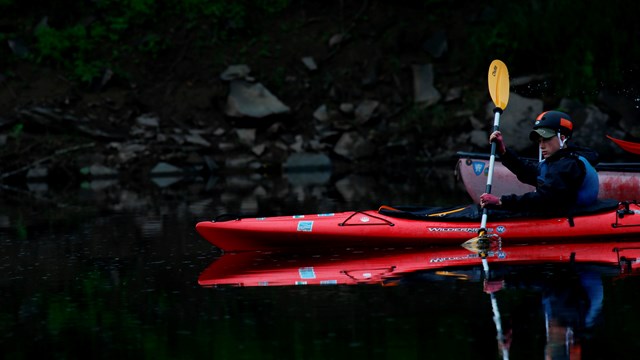 Young boy in kayak cuts through the water.