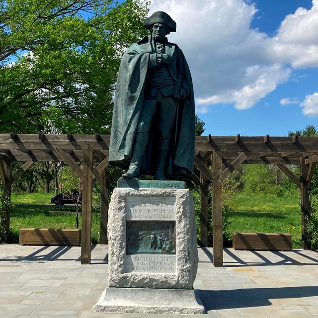 A bronze statue of a man wearing a military uniform on a stone pedestal