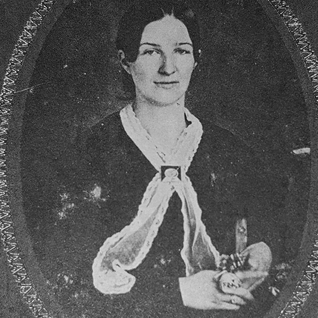 A black and white photograph of Emma Balfour  wearing a long white scarf around her neck.