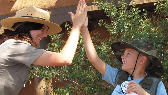 Ranger and junior ranger high fiving.