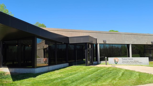 The front of the visitor center is made of concrete and dark glass. 