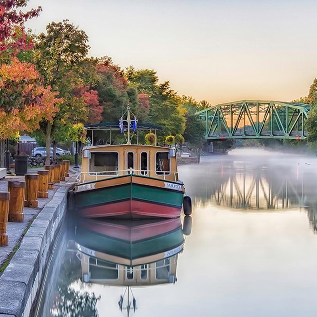 A canal boat sitting alongside a dock in autumn