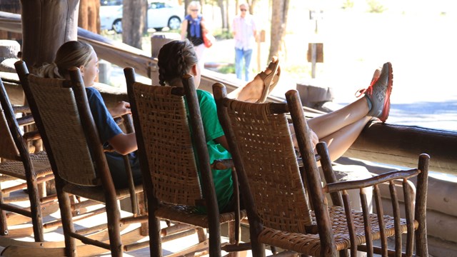 Two girls sit on a porch with legs stretched out in front