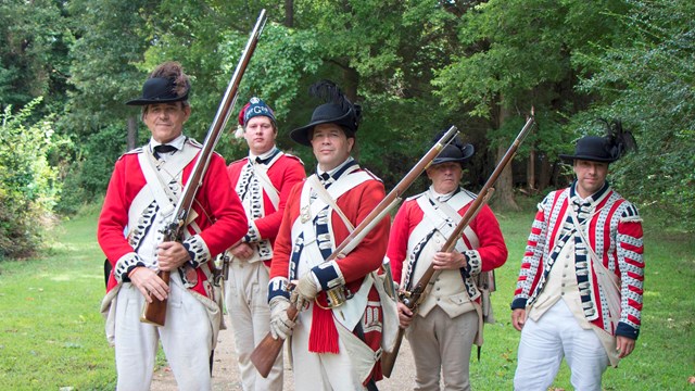5 British soldiers stand looking 